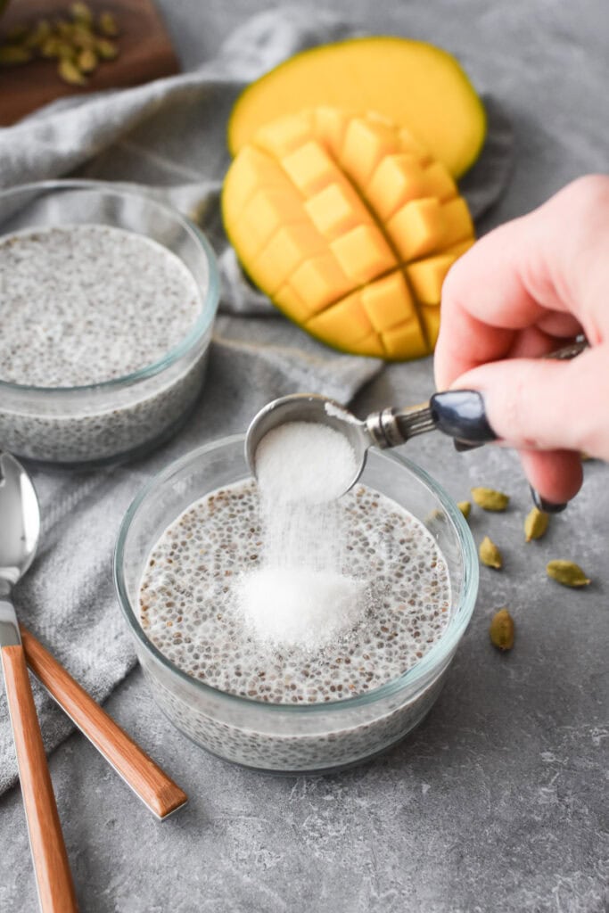 Adding sugar to a glass bowl of chia pudding