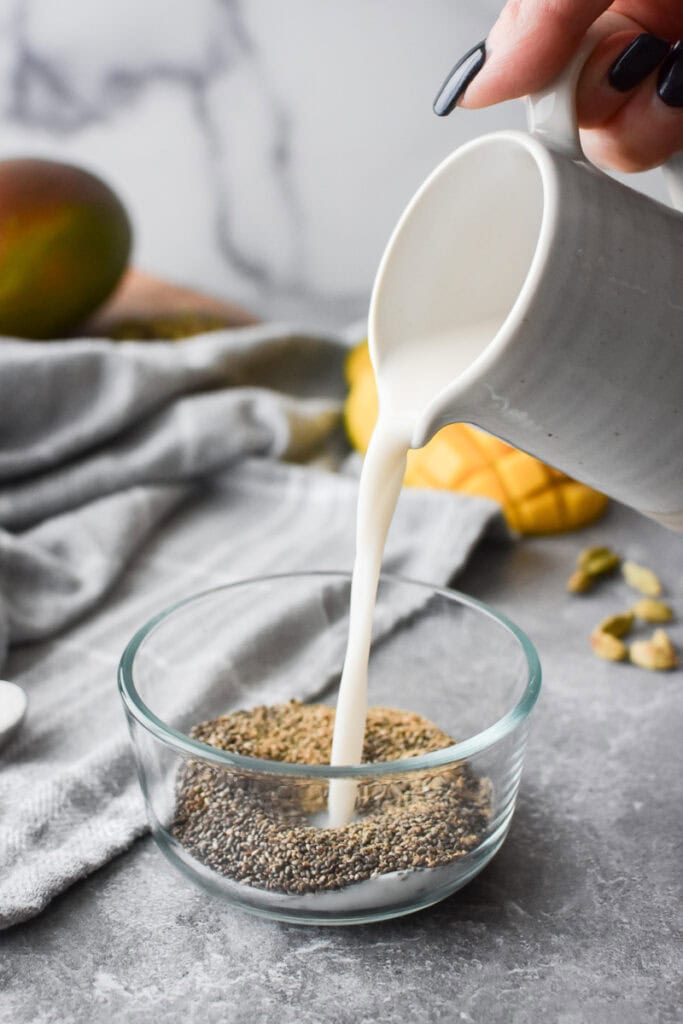 Adding milk to chia seeds in a glass bowl