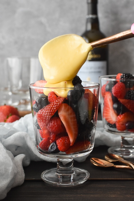 Spooning zabaglione onto a cup of fresh berries