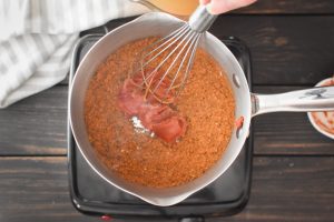 whisking spices and tomato paste in a pot