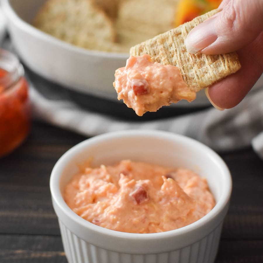 A cracker being dipped into pimento cheese dip