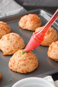 using a silicone brush to add the butter topping to cheddar bay biscuits