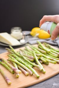 spraying olive oil on asparagus