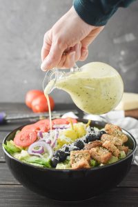 pouring the dressing on an olive garden salad