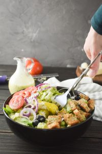 mixing an olive garden salad with salad tongs