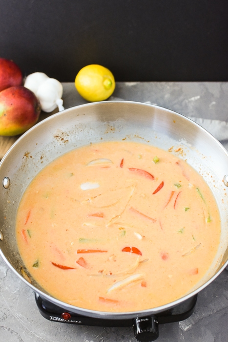 all of the liquid ingredients have been added to a pan of thai mango curry
