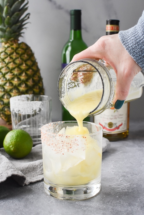 pouring a margarita into a glass