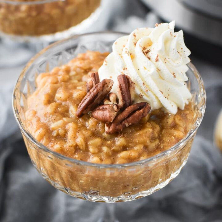 a glass of pumpkin rice pudding with pecans and coco whip
