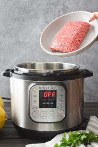Adding beef to an Instant Pot.