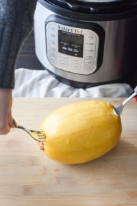 Removing a spaghetti squash from the Instant Pot with two forks.
