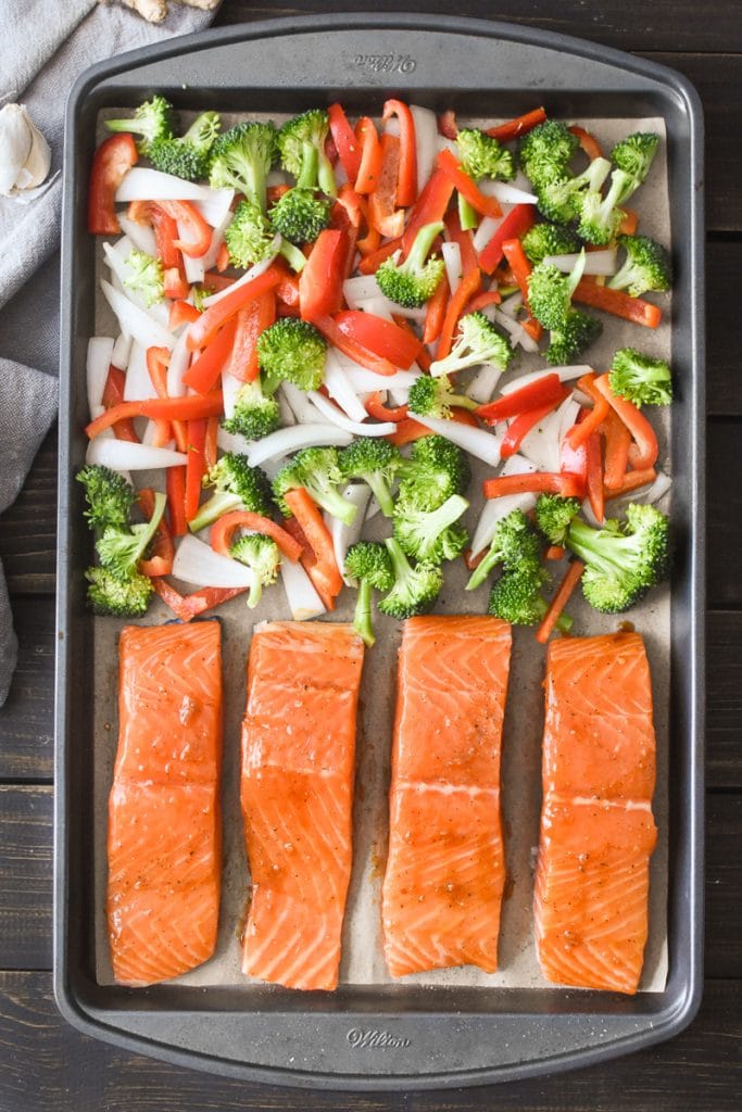 raw salmon basted in teriyaki sauce with vegetables on a sheet pan