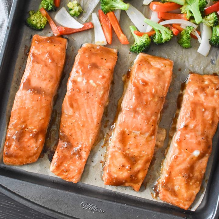 A sheet pan with teriyaki salmon and roasted vegetables on it.