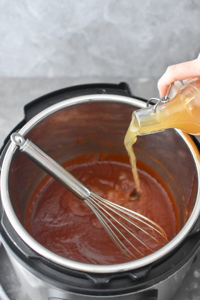 Whisking apple cider into bbq sauce in an Instant Pot.