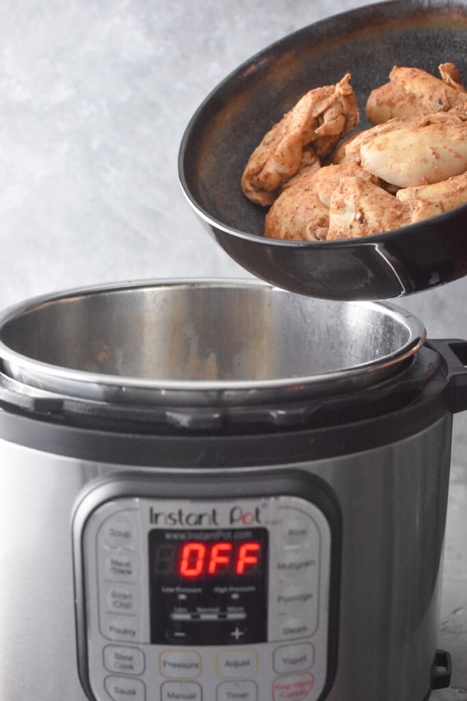 Adding cooked chicken thighs to an Instant Pot.