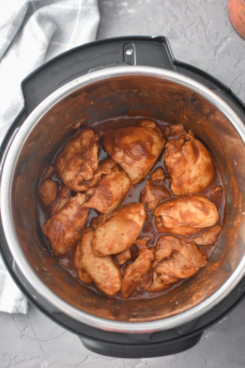 An Instant Pot full of Apple Cider BBQ Sauce-coated chicken thighs.