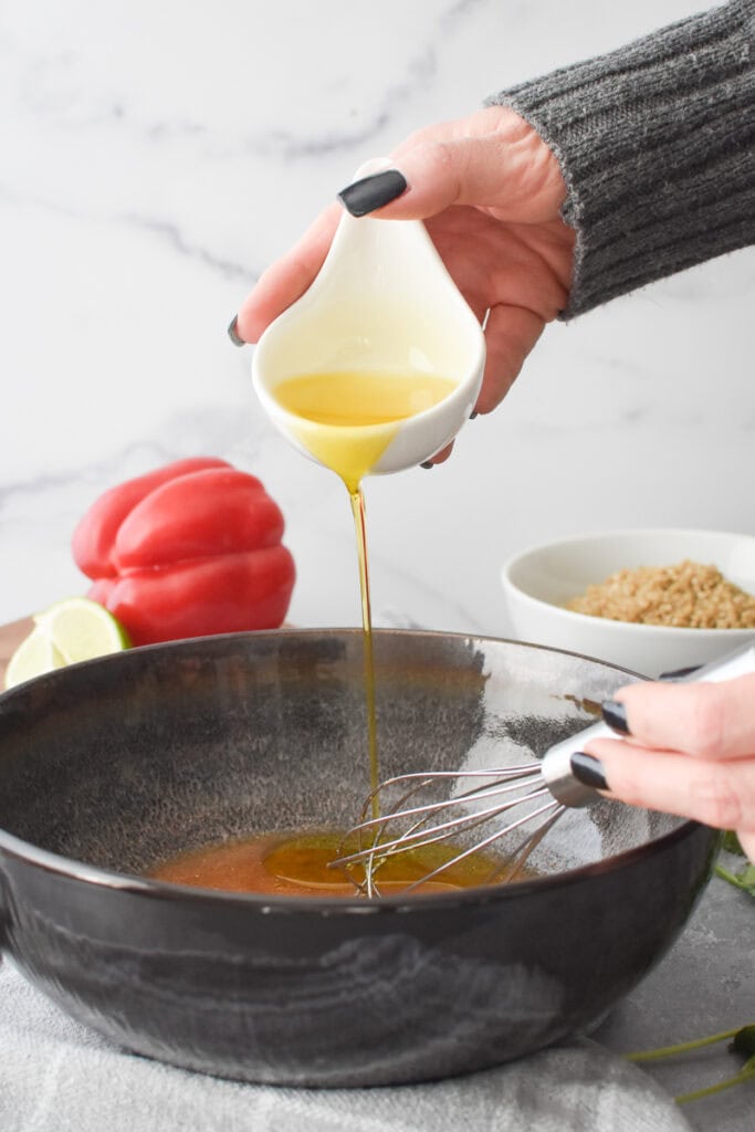 Drizzling in olive oil while whisking to make a dressing