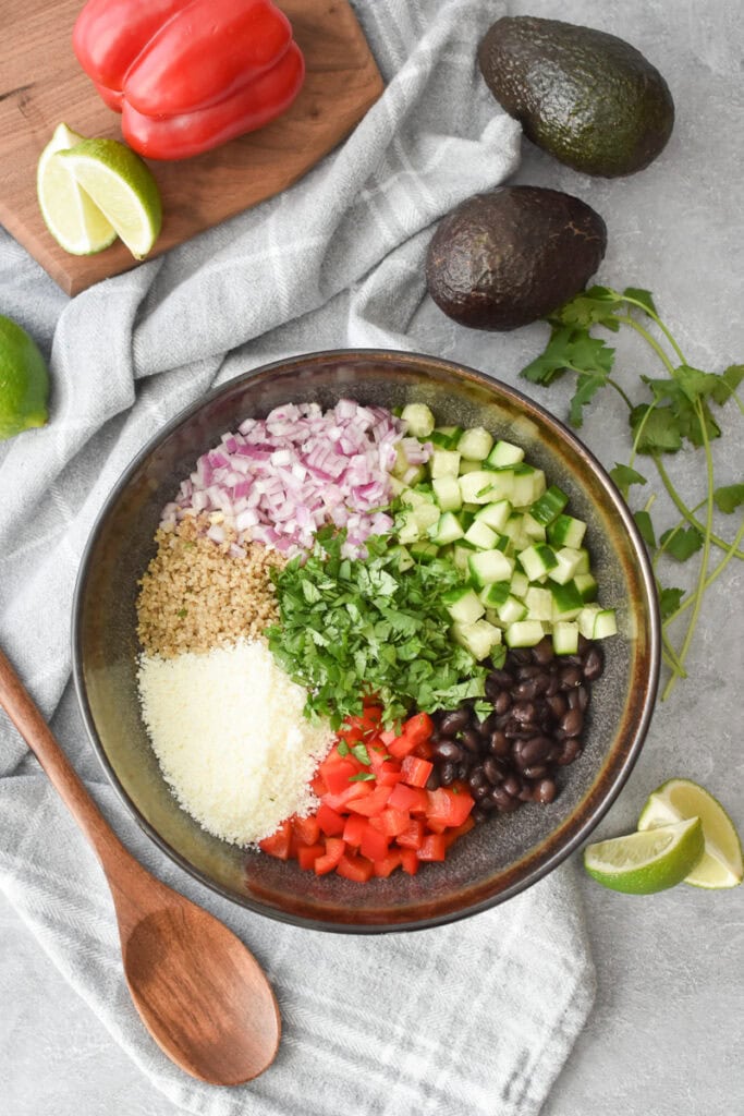 All of the ingredients for Cilantro Lime Quinoa Salad added to a large brown bowl.