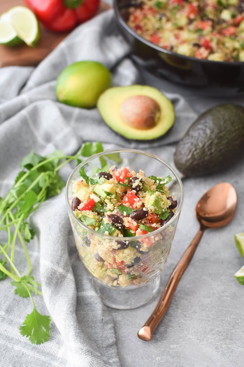 A clear glass filled with Cilantro-Lime Quinoa Salad with Avocado.