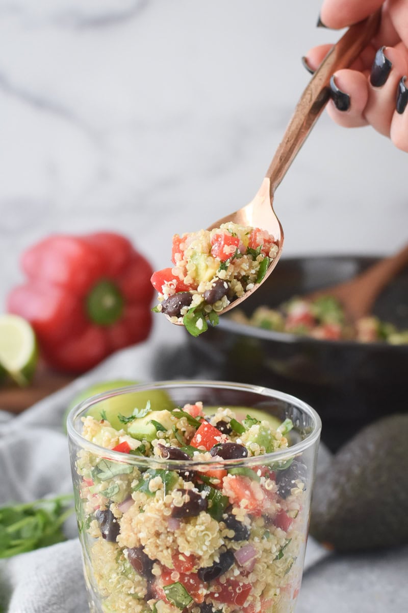 A close-up image of a spoonful of cilantro-lime quinoa salad with avocado
