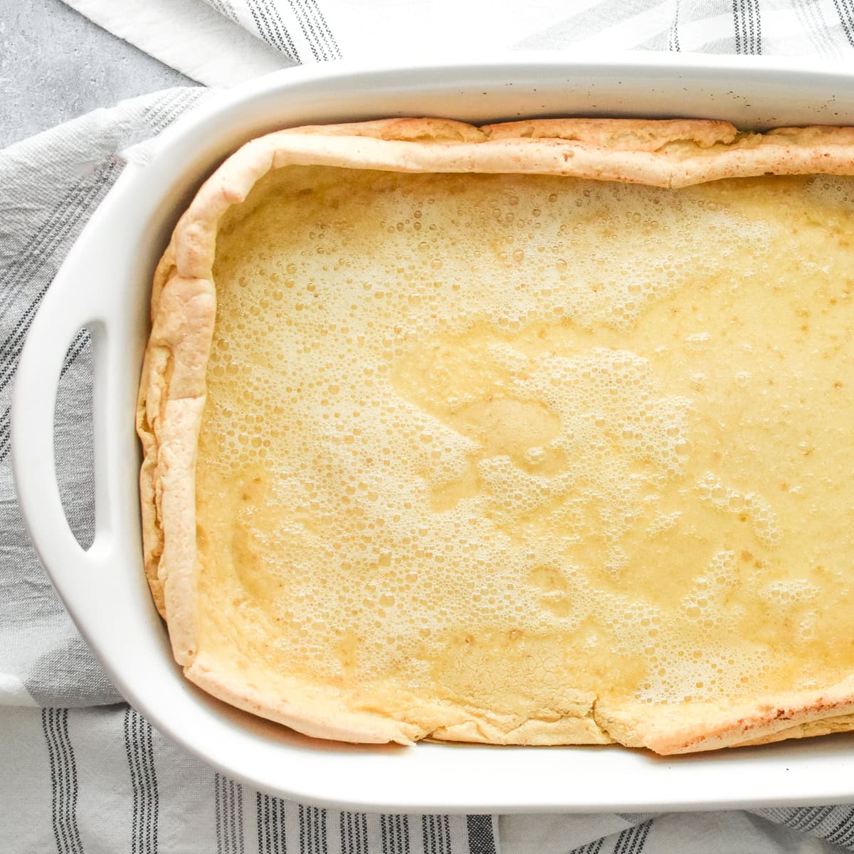 A German Pancake in a white 9 by 13 ceramic casserole dish.